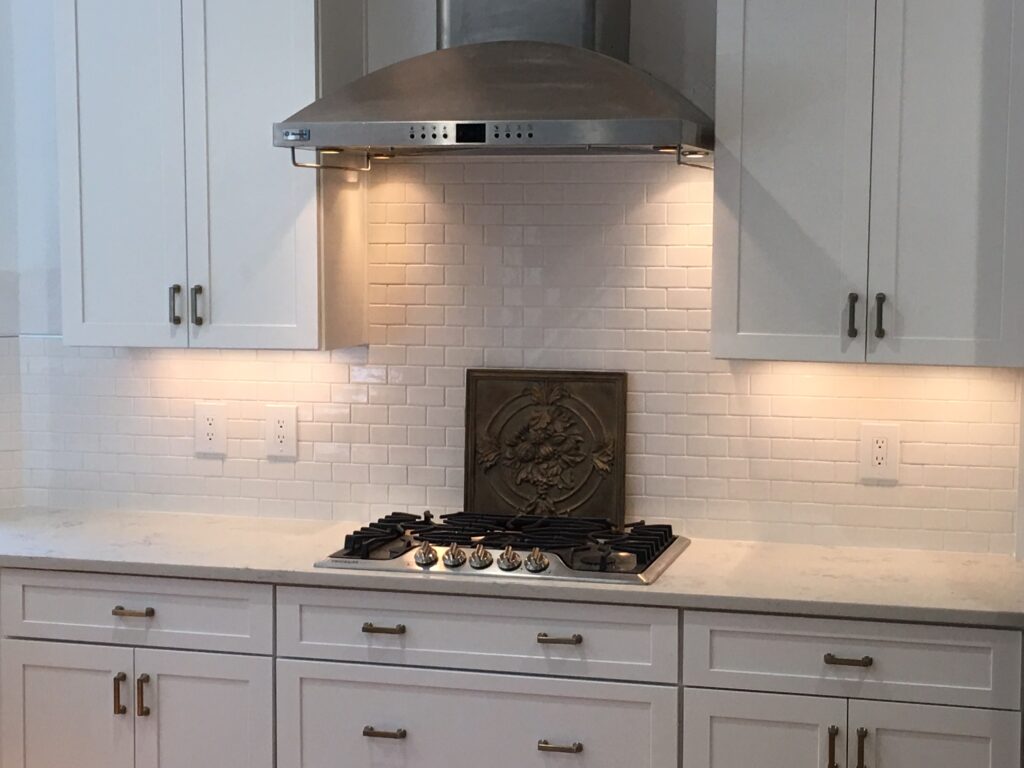 A kitchen with white cabinets and a stove.