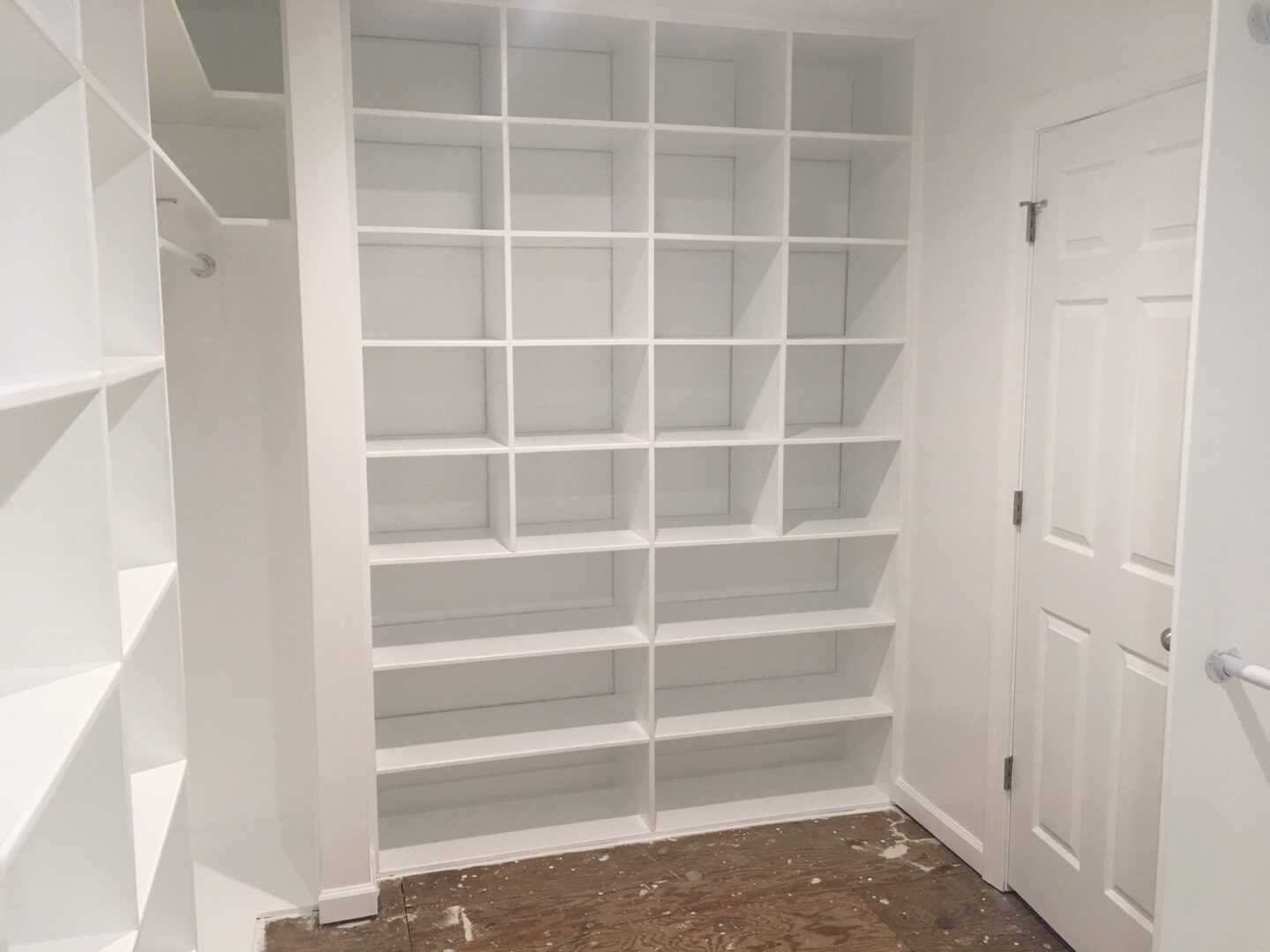 A white shelving unit in the corner of a room.