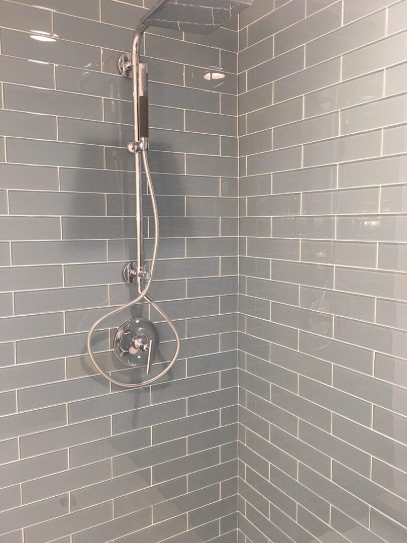 A shower head is hanging in the corner of a bathroom.