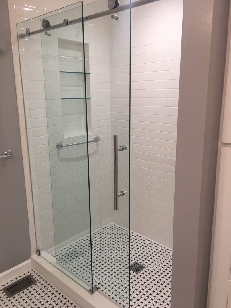 A bathroom with a glass shower door and tiled walls.