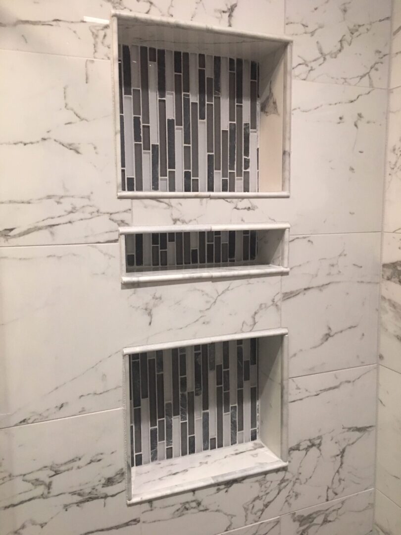 A bathroom with marble walls and tiled shelves.