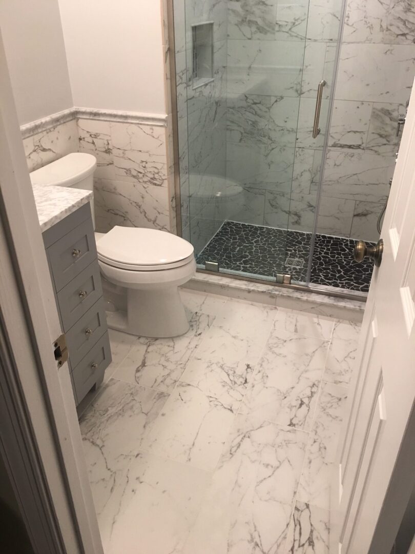 A bathroom with marble tile and white walls.