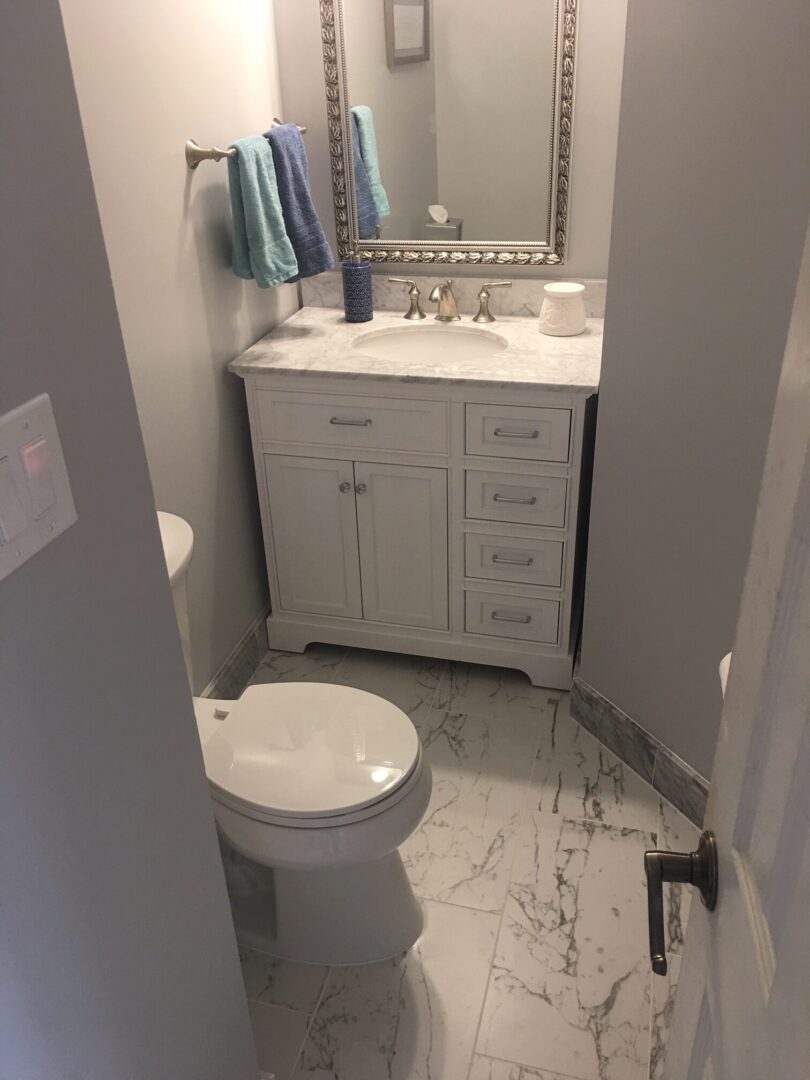 A bathroom with white cabinets and marble floors.