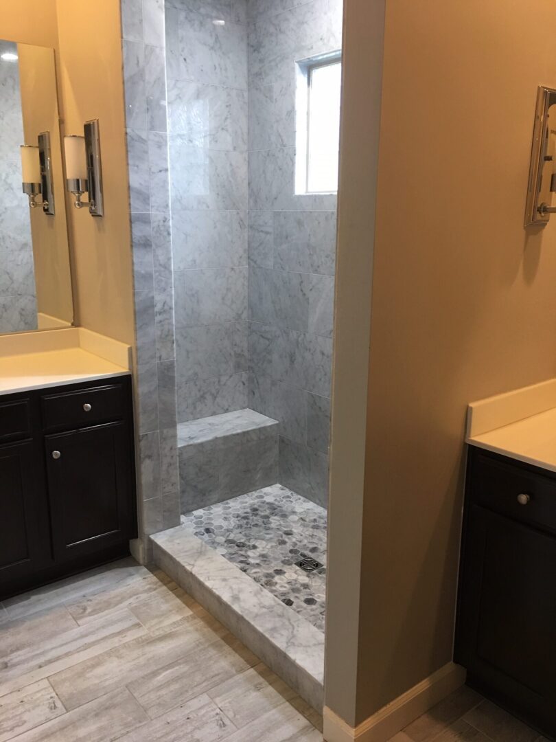 A bathroom with two sinks and a walk in shower.