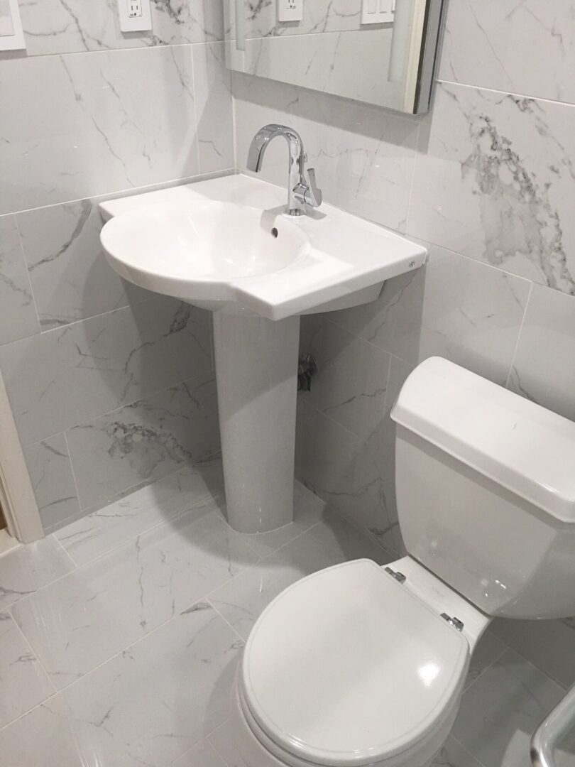 A bathroom with white tile and marble walls.