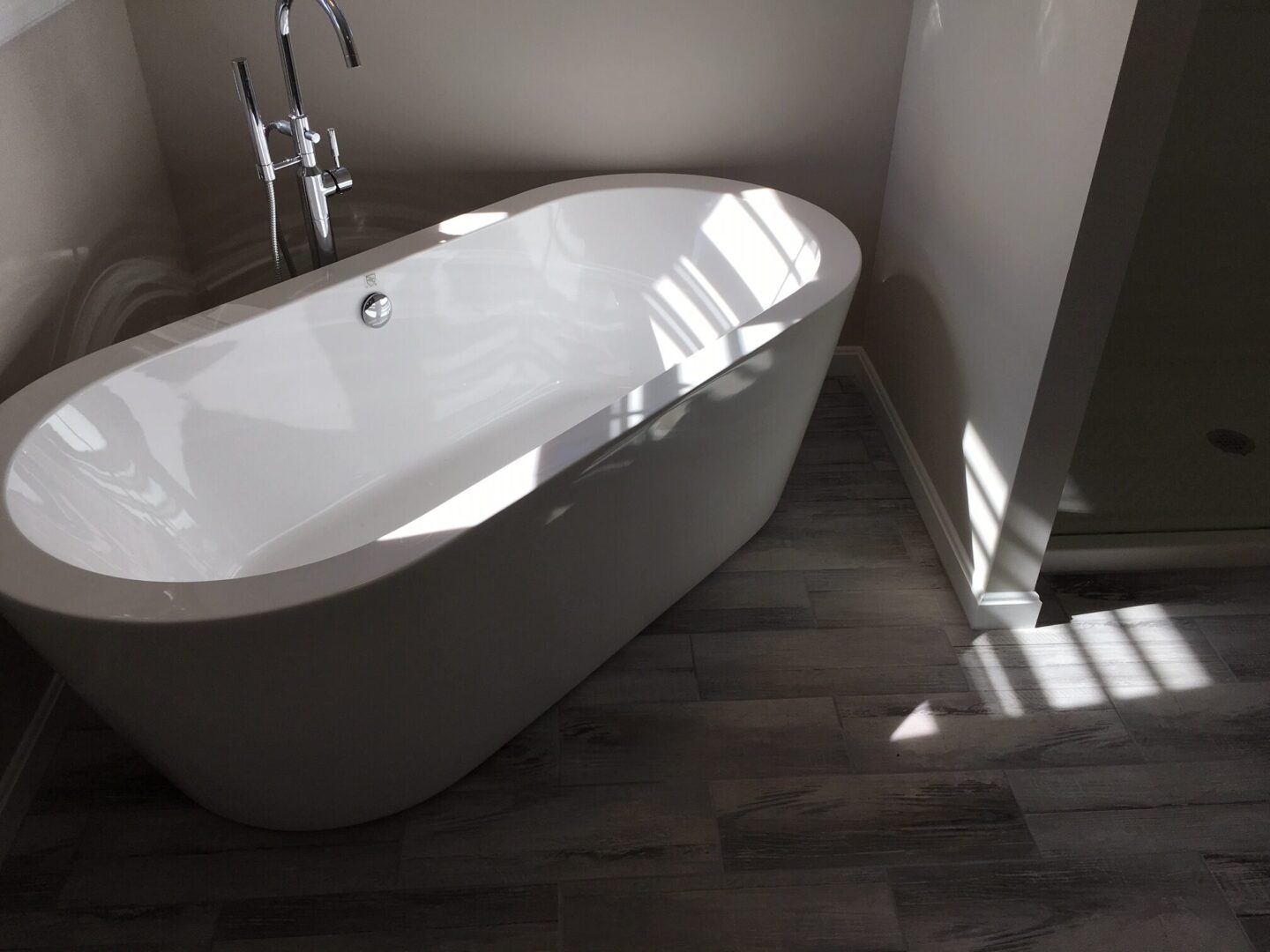 A bathroom with a tub and tile floor.