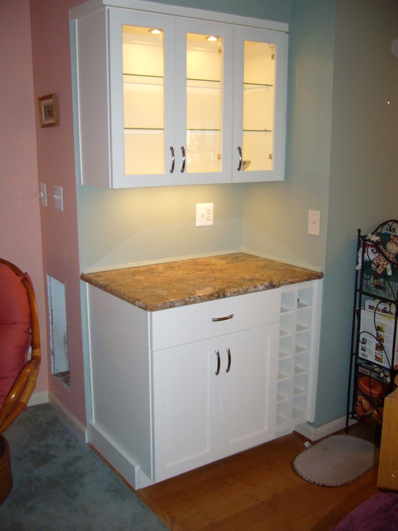 A kitchen with white cabinets and marble counter tops.