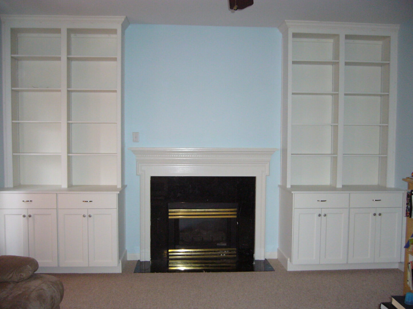 A fireplace with built in bookcases and cabinets.