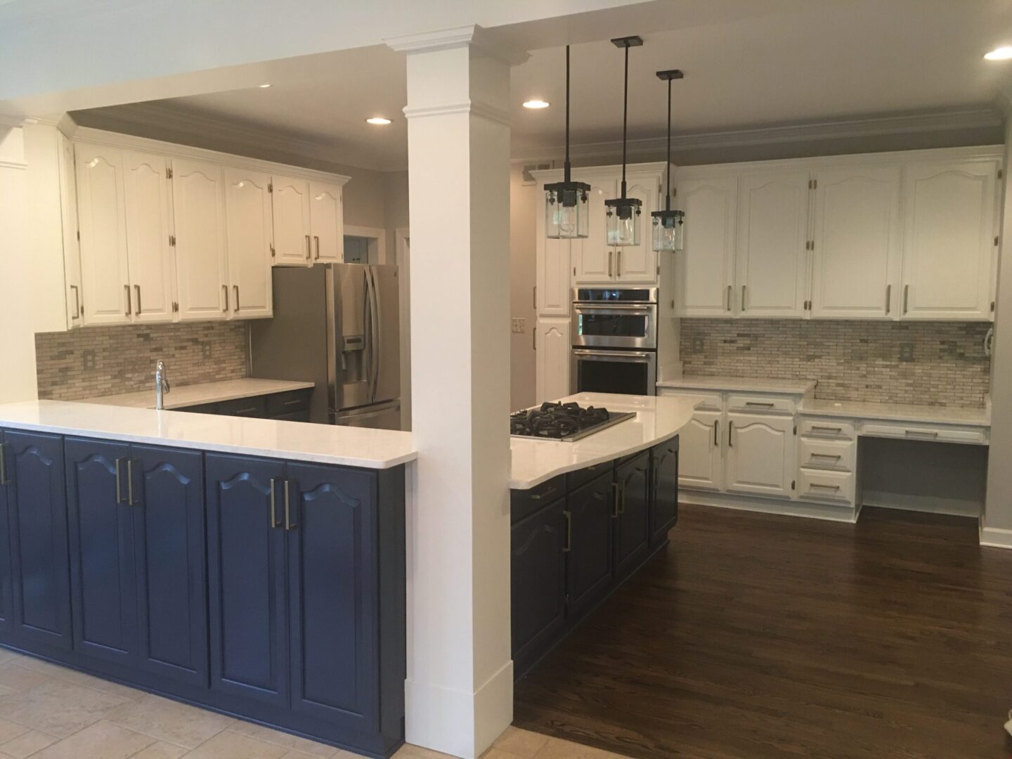 A kitchen with white cabinets and blue island.