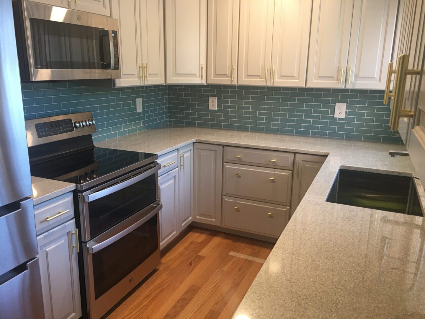 A kitchen with white cabinets and blue tile backsplash.