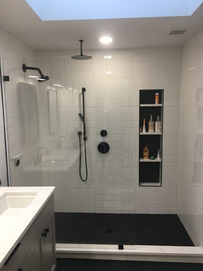 A bathroom with white tile and black accents.