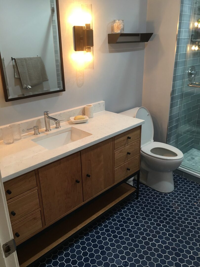 A bathroom with a toilet, sink and mirror.