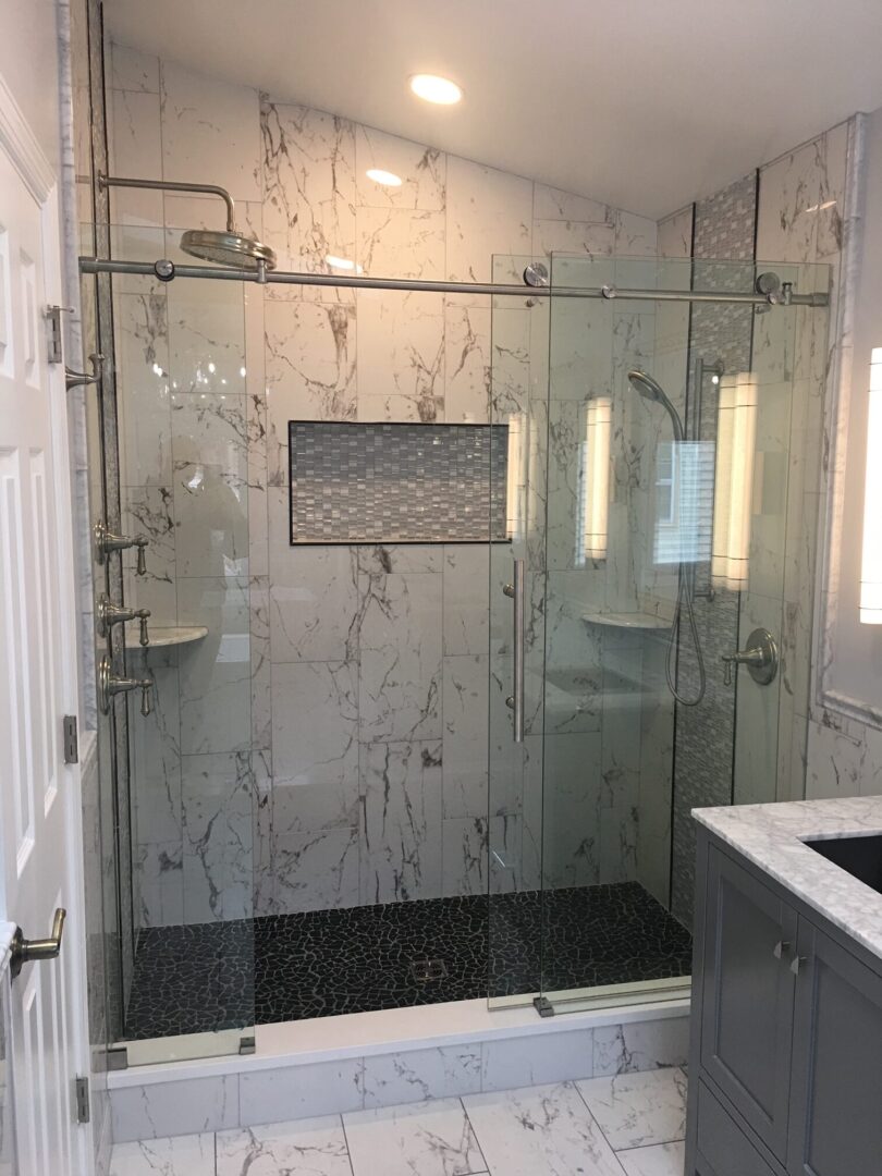 A bathroom with marble walls and black tile.